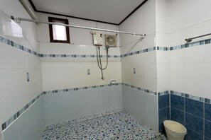 Une salle de bain avec des carreaux blancs et bleus, une douche, des toilettes et une fenêtre.