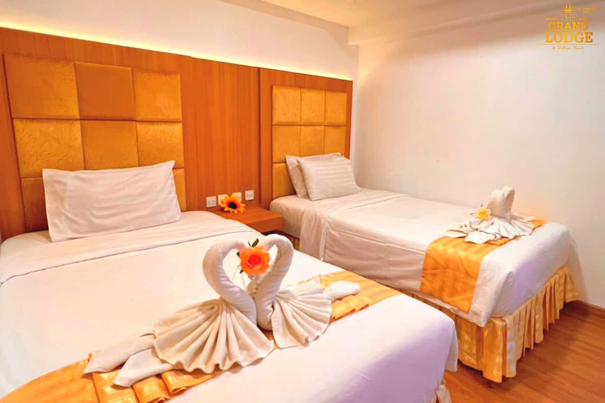Quarto de hotel com duas camas, cada uma com cabeceira, e piso de madeira.