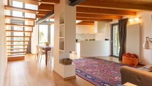 A modern interior with a wooden staircase, a dining area, a kitchen, and a living space with a large rug and a sofa. - Nice apartment in villa for 6 people with WIFI and terrace (Colico)