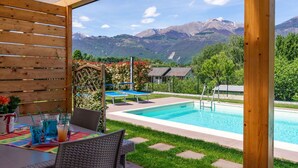 A poolside area with a view of mountains, a table with drinks, and outdoor seating. - Lovely apartment in villa for 5 guests with pool, WIFI, TV and terrace (Colico)