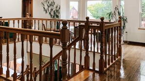 A spacious room with wooden flooring, a wooden staircase with balusters, and large windows allowing natural light. - The Niseko Ski Lodge - Higashiyama (Niseko)