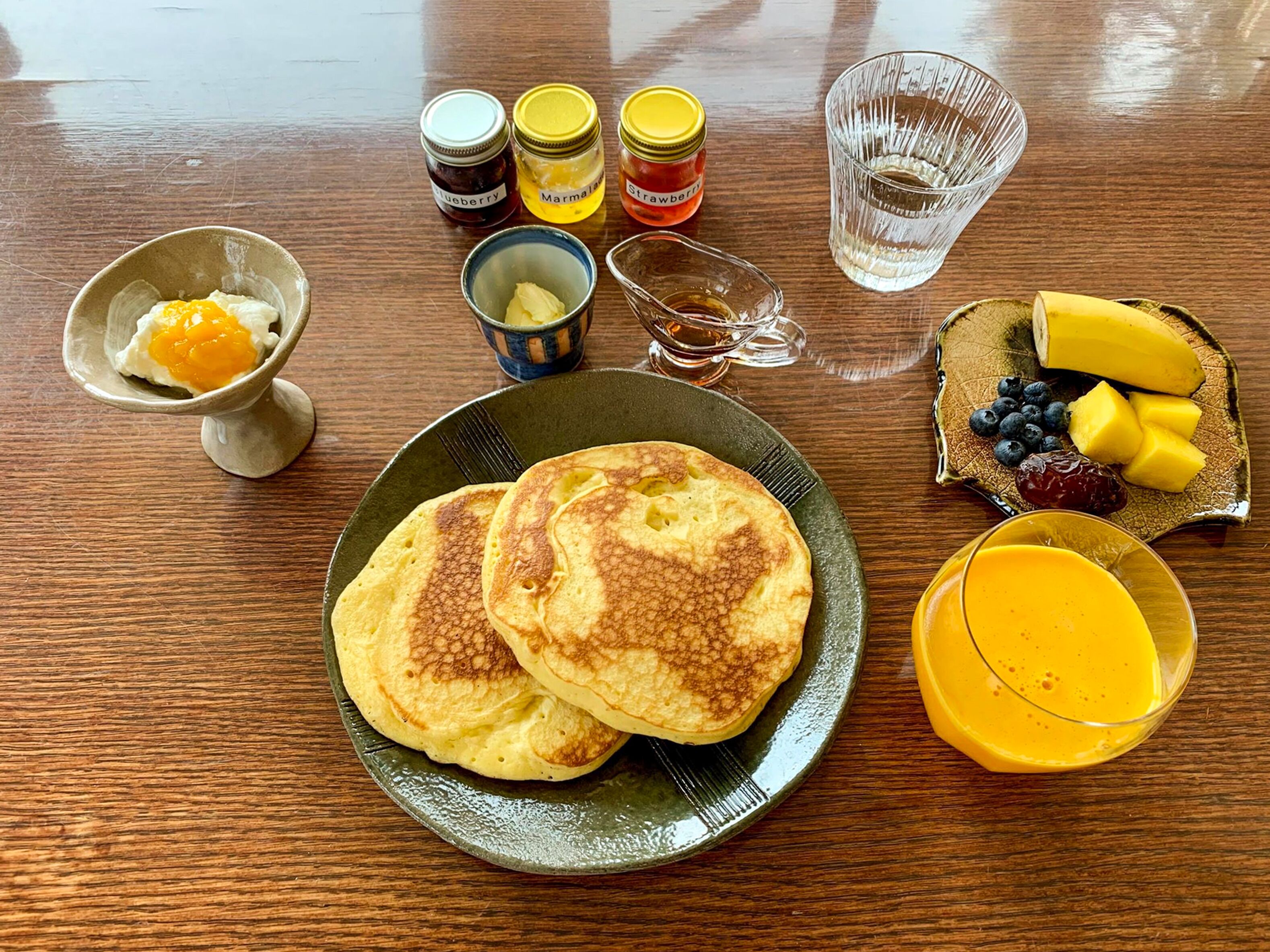 Ein Frühstückstisch mit Pfannkuchen, Obst und Beilagen.