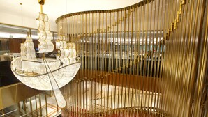 A modern interior with a distinctive golden spiral staircase and a large, ornate chandelier. - Holiday Inn Dhaka City Centre by IHG (Dhaka)