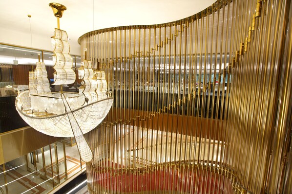 A modern interior with a distinctive golden spiral staircase and a large, ornate chandelier. - Holiday Inn Dhaka City Centre by IHG (Dhaka)