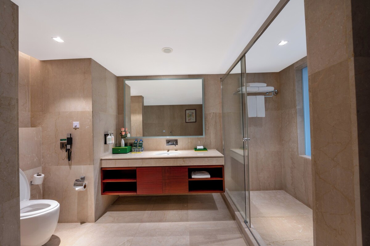 A modern bathroom with a glass shower enclosure, a large mirror, and a vanity with a sink and storage.