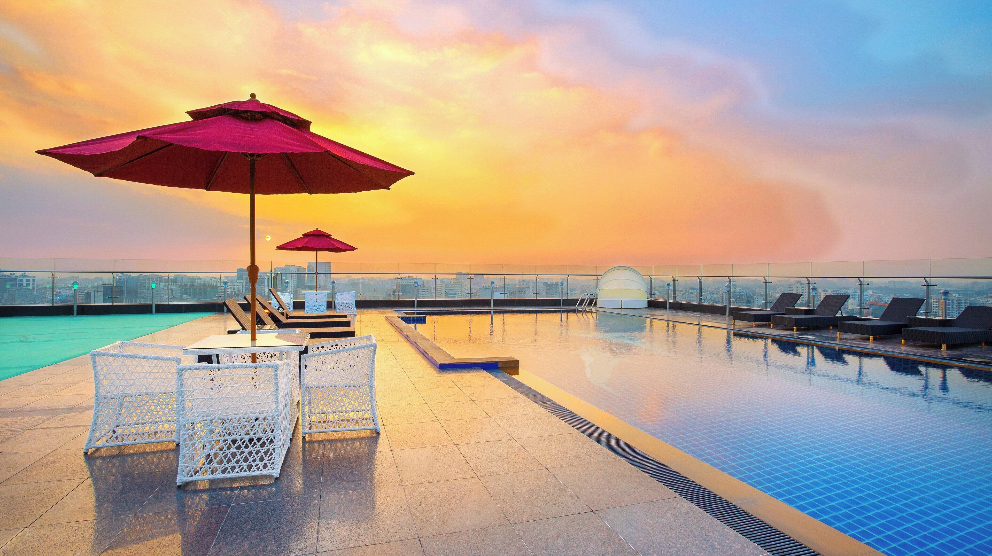 Una piscina al aire libre, sombrillas, sillones reclinables de piscina