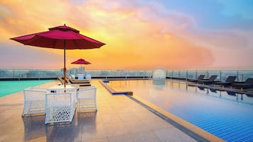 Una piscina al aire libre, sombrillas, sillones reclinables de piscina