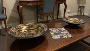 A dining table with two large decorative bowls, a magazine, and a red vase with flowers. - Boutique apartment in the heart of the Adelaide CBD (Adelaide)