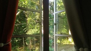 A window with a view of a forested area outside. - Guesthouse Beluru (Kuala Kangsar)