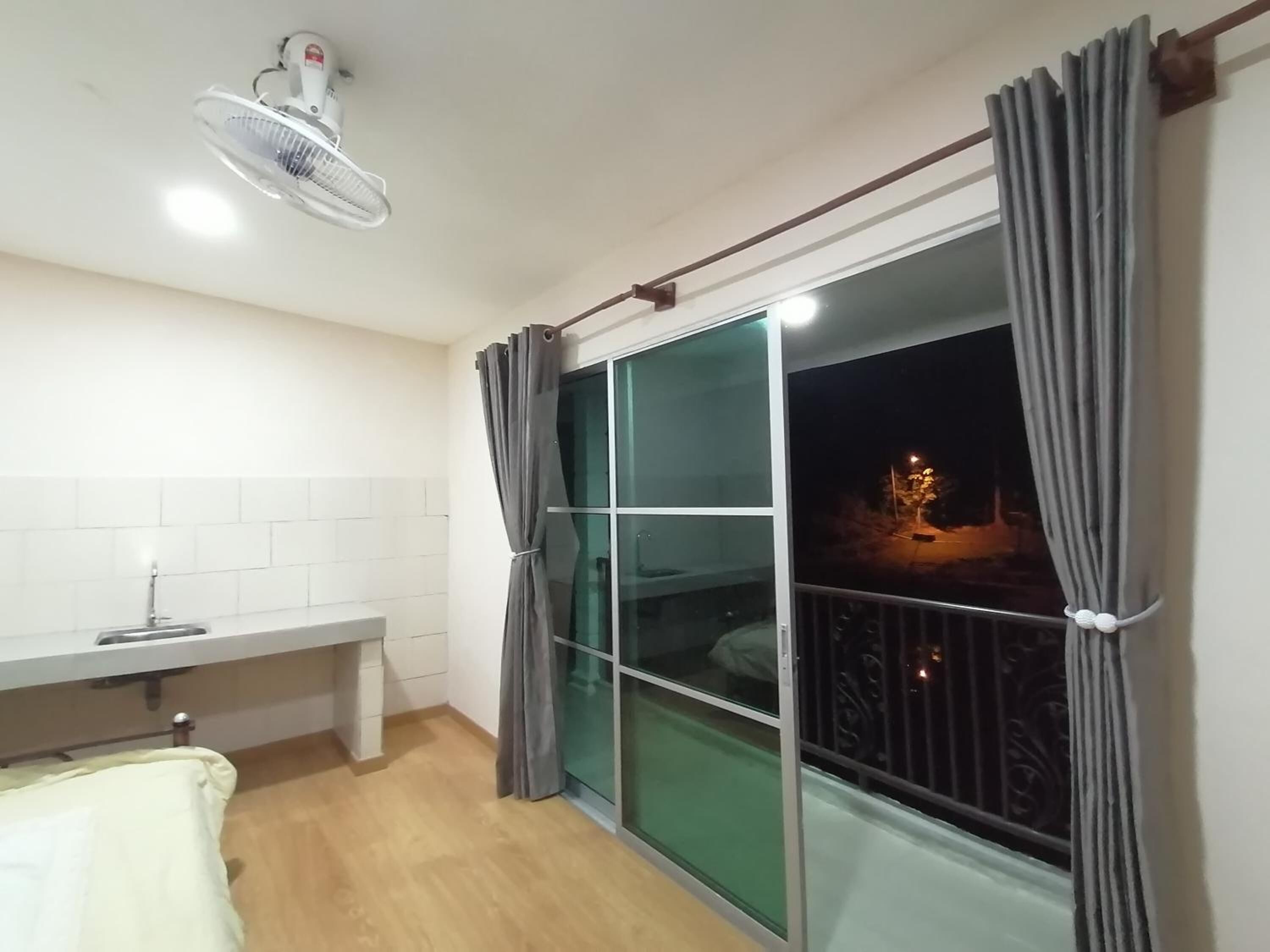 Une pièce dotée d’une grande fenêtre, d’un ventilateur de plafond, d’un lavabo et de toilettes.