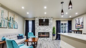 A modern living room with a fireplace, a sofa, a coffee table, and a dining area. - Stylish Condo near SMU, NorthPark & Greenville Ave with Pool (Dallas)