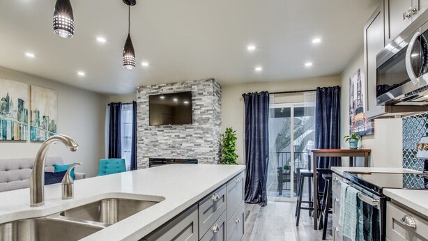 A modern kitchen with a large island, stainless steel appliances, and a stone accent wall. - Stylish Condo near SMU, NorthPark & Greenville Ave with Pool (Dallas)