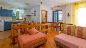 A cozy room with a wooden bench, a sofa, and a dining table. - Holiday home mit Klimaanlage und Balkon (Crikvenica)