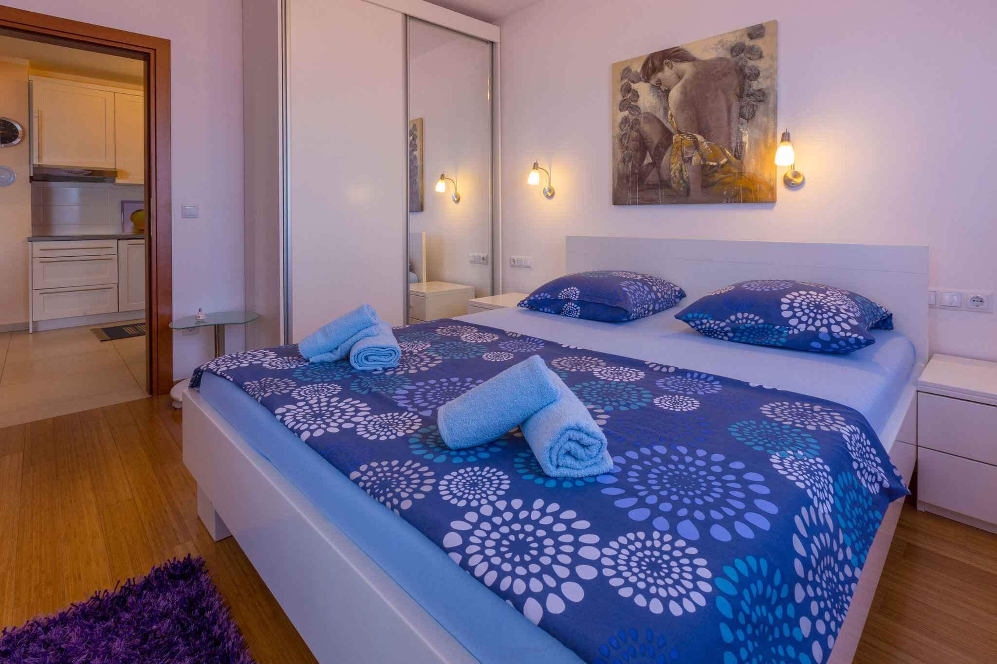 Une chambre à coucher comprenant un lit, deux tables de chevet, une commode, un miroir et un tableau accroché au mur.