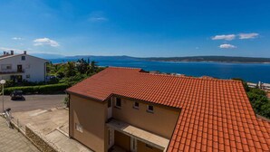 Un quartier résidentiel situé sur la côte, avec une maison dotée d’un toit recouvert de tuiles rouges et offrant une vue sur la mer.