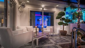 A modern outdoor seating area with white furniture, a table with candles, and a potted tree. - View Talay Villas Pattaya (Pattaya)