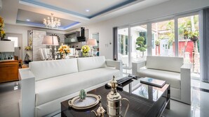 A modern living room with a white sofa, a coffee table with decorative items, and a view of the outside through large windows. - View Talay Villas Pattaya (Pattaya)
