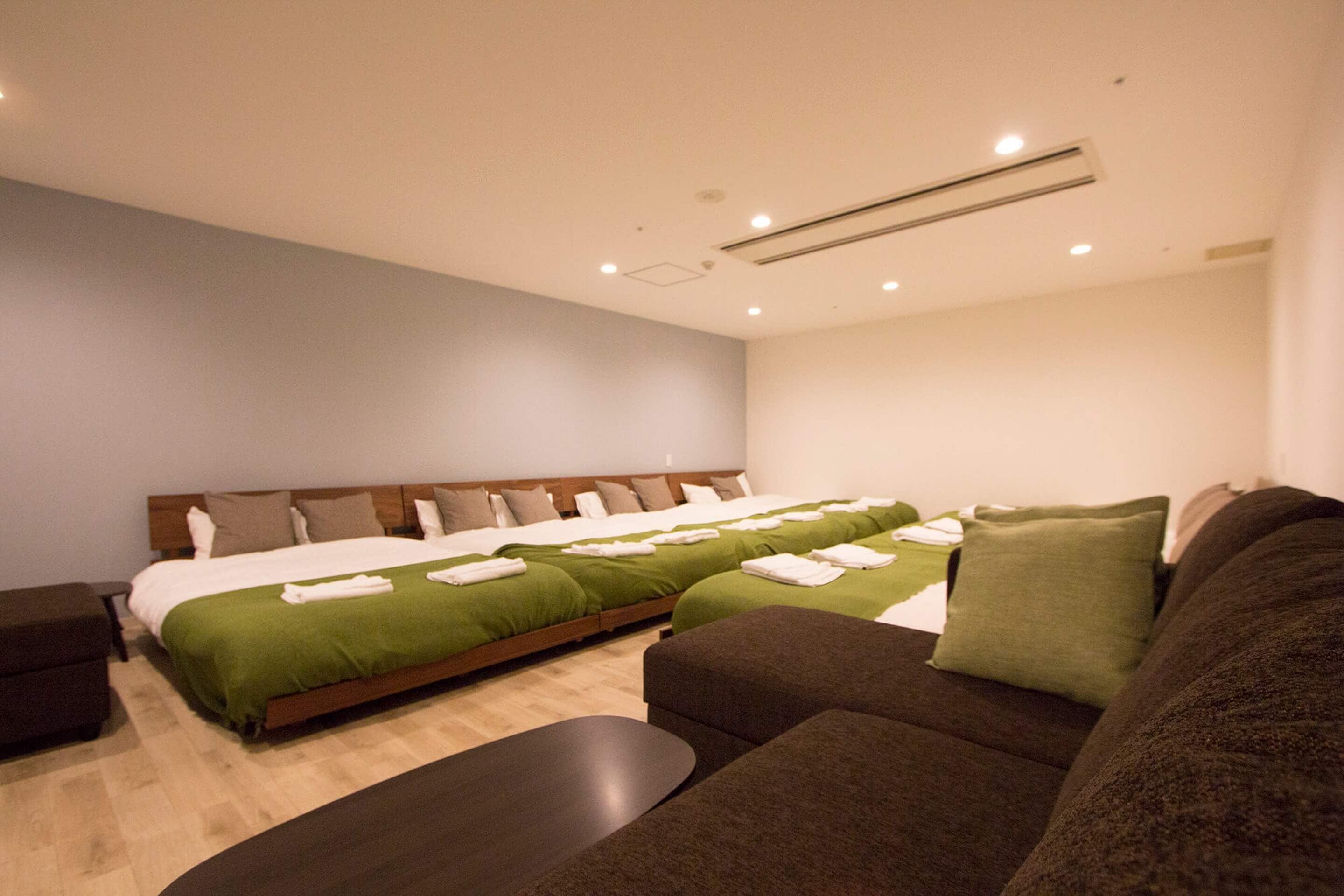A hotel room with a large bed, a sofa, and a small table.