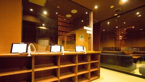 Un espace d’accueil avec un comptoir où sont exposés trois ordinateurs portables, une cloison en verre et un panneau avec du texte.