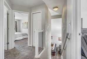 Een gang die leidt naar een slaapkamer met een bed, een radiator en een trap.