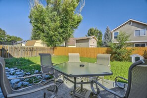 Een achtertuin terras met een tafel en stoelen, omgeven door een houten schutting en een boom.