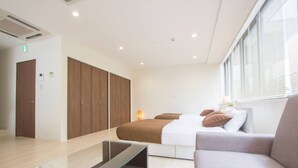 Una habitación de hotel moderna con cama, sofá, una mesita de vidrio y un armario.