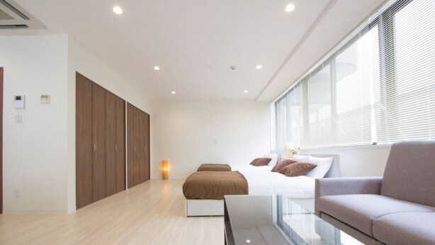 Un dormitorio moderno con cama, una mesita de vidrio, un sofá y un armario.