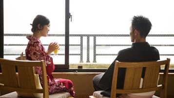Una pareja sentada a una mesa junto a una ventana con vistas a un balcón.