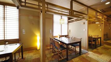 Une pièce de style japonais traditionnel, avec un sol recouvert de tatamis, une table basse et des chaises, ainsi que des portes coulissantes.