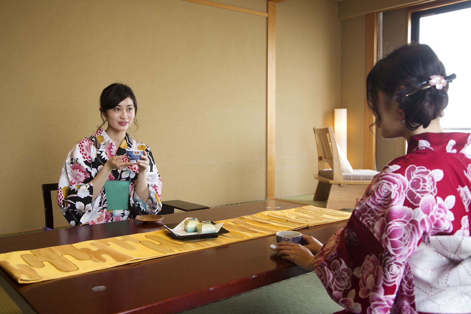 A traditional Japanese meeting room with tatami mats, a low table, and a wooden chair.