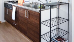 A modern kitchen with wooden cabinets, a stainless steel sink, and a black range hood. - Trailside Apartments & Chalet (Kutchan)