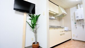A kitchen with a flat-screen TV mounted on the wall, a potted plant, and a water heater.