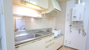 A kitchen with a stainless steel sink, a white countertop, beige cabinets, and a built-in dishwasher.
