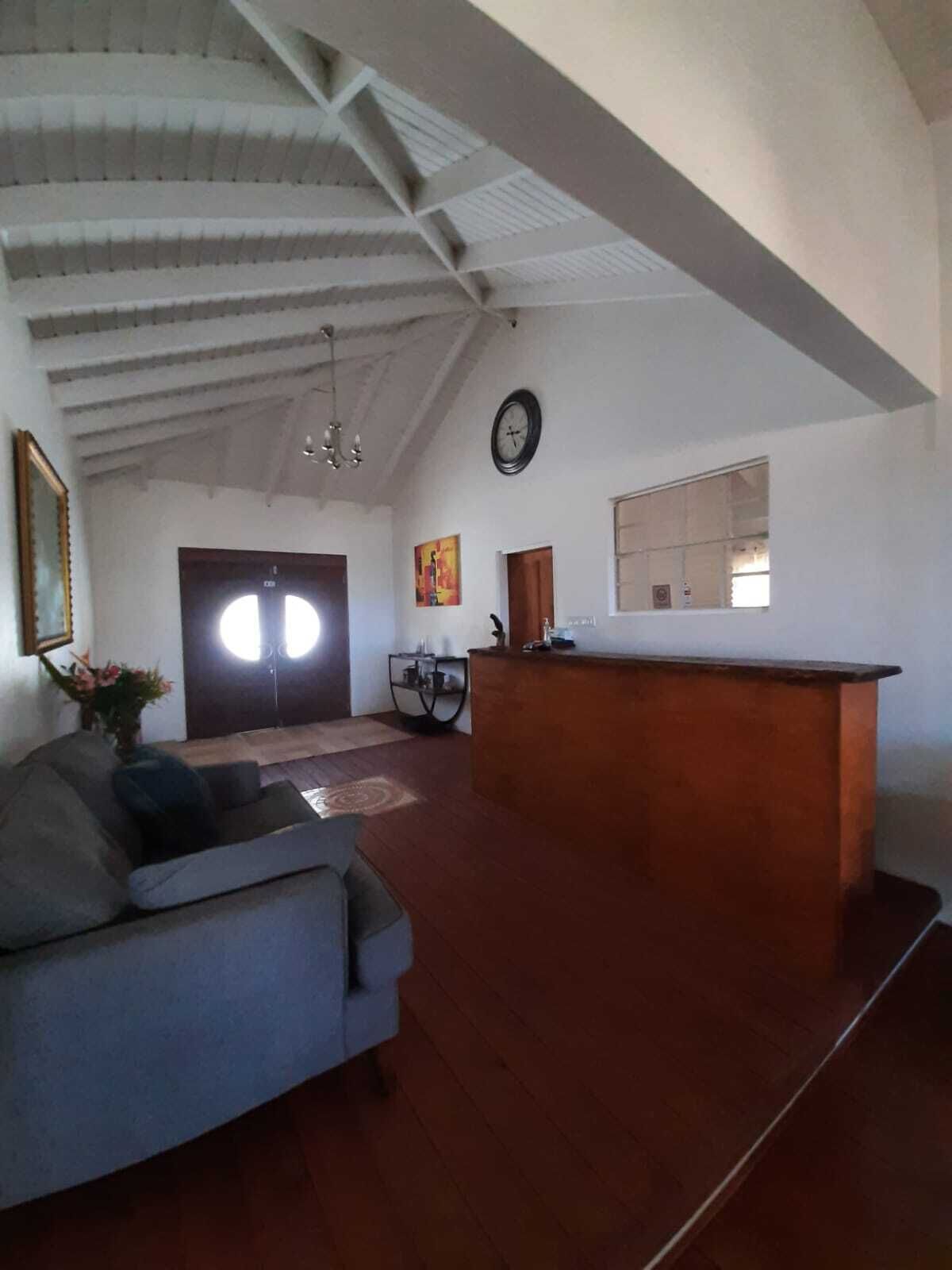 Ein geräumiges Wohnzimmer mit hoher Decke, einer Couch, einem Couchtisch, einem Holzerrezeptionstisch und einem großen Fenster.