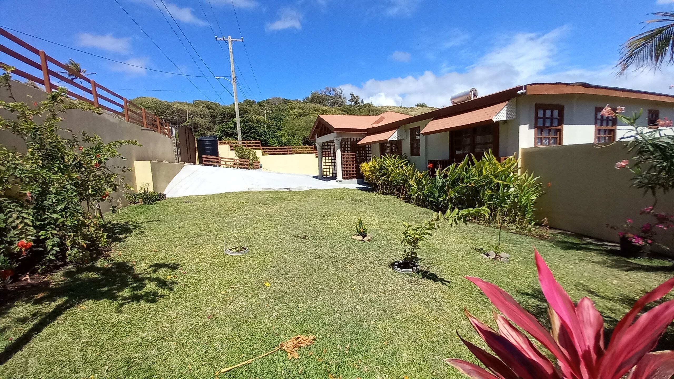 A residential property with a well-maintained lawn, a small garden area, and a two-story building with a red roof.