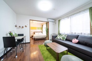 A modern living room with a sofa, a dining table, and a bed. - Stay inn FREE (Sapporo)