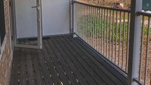 Uma varanda com vista para uma montanha nevada, uma porta e um corrimão.