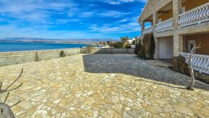 A coastal property with a stone patio, a pool, and a view of the sea.