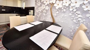 A modern dining area with a black table, white chairs, and a decorative wall with white flowers.