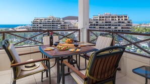 Een balkon met een tafel voor twee, met uitzicht op de stad en de zee.
