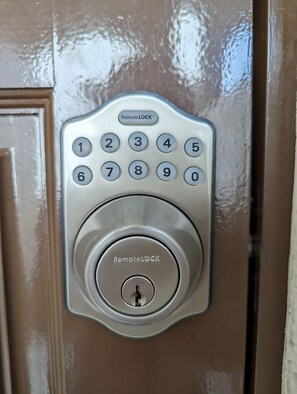 A door with a numeric keypad and a keyhole, labeled "RemoteLOCK." - Tsukiyume-kan (Osaka)