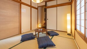 Ein traditioneller japanischer Raum mit Tatami-Boden, Shoji-Schirmwänden und einem niedrigen Holztisch mit Kissen.