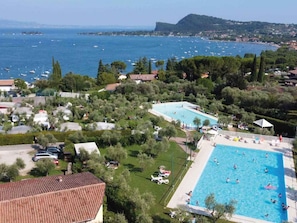 A residential area with a large swimming pool surrounded by greenery and houses.