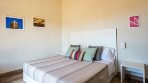 Une chambre à coucher avec un lit, des oreillers, une table de chevet et deux tableaux accrochés au mur.