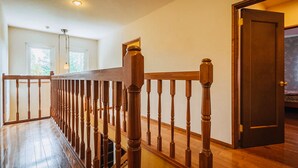 A wooden staircase with a railing, a wooden door, and a window with a view of greenery. - Chalet Banff (Niseko)
