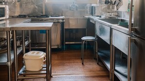 A kitchen with stainless steel appliances, a large window, and a wooden floor. - Chalet Banff (Niseko)