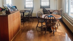 A dining area with a wooden table and chairs, a reception desk, and windows with blinds. - Chalet Banff (Niseko)