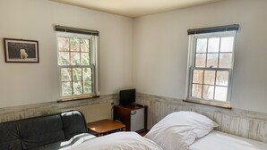 A room with two beds, a sofa, a small table with a TV, and windows with blinds. - Chalet Banff (Niseko)