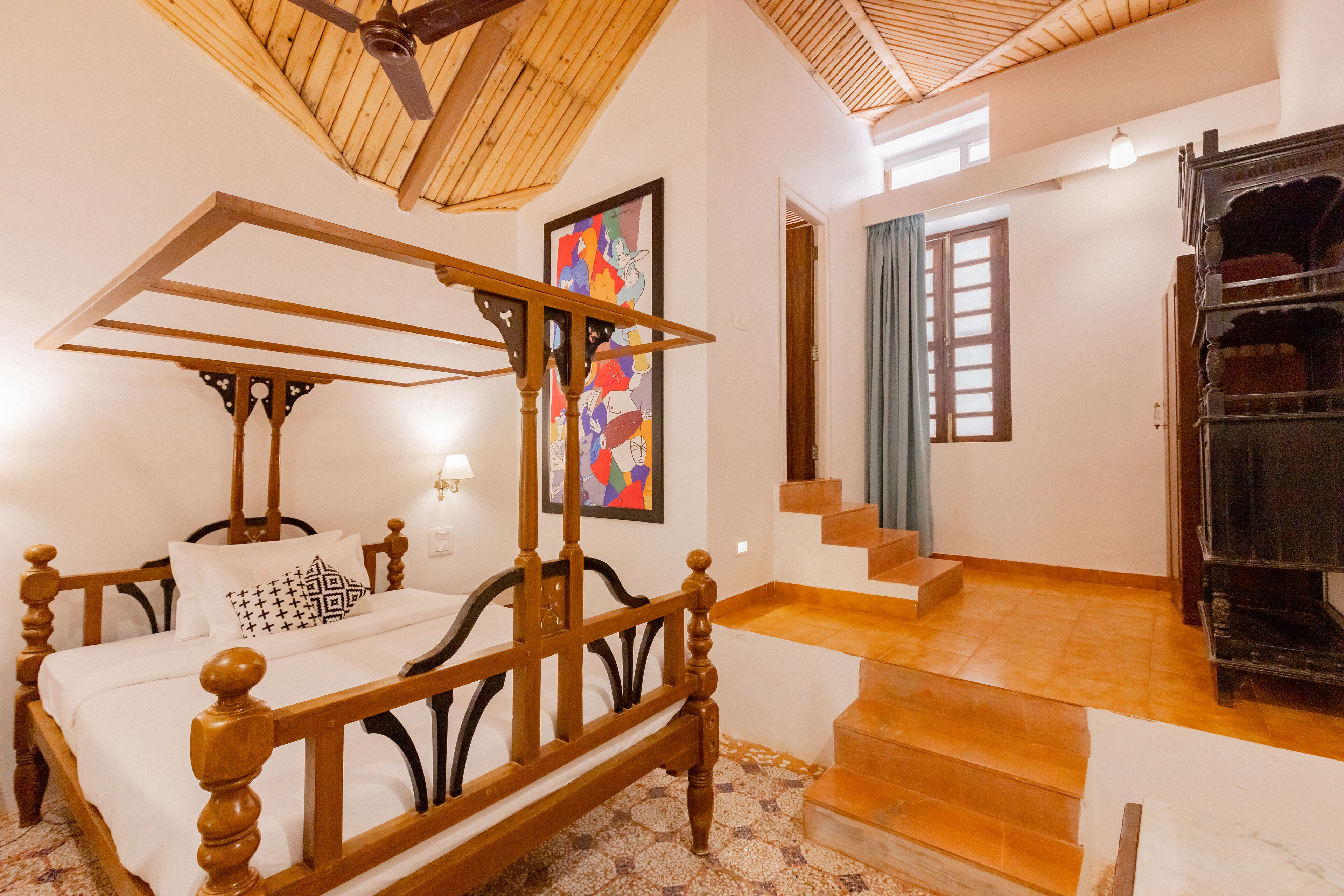 Quarto com cama de madeira com dossel, escada e lareira.