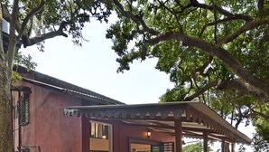 A house with a covered porch, a staircase, and a garden area. - Radha Cottage (Karjat)